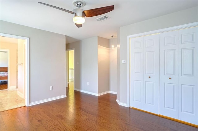 unfurnished bedroom with a closet, dark hardwood / wood-style flooring, and ceiling fan