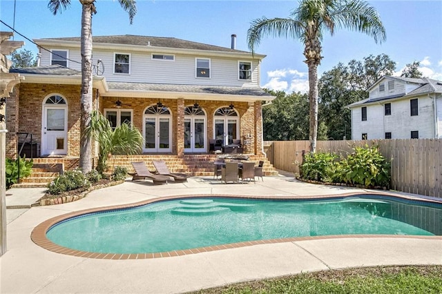 back of property with a fenced in pool and a patio area