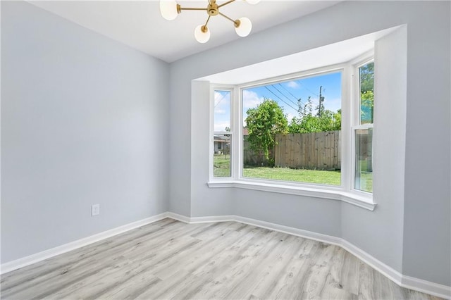 empty room featuring an inviting chandelier and light wood-type flooring