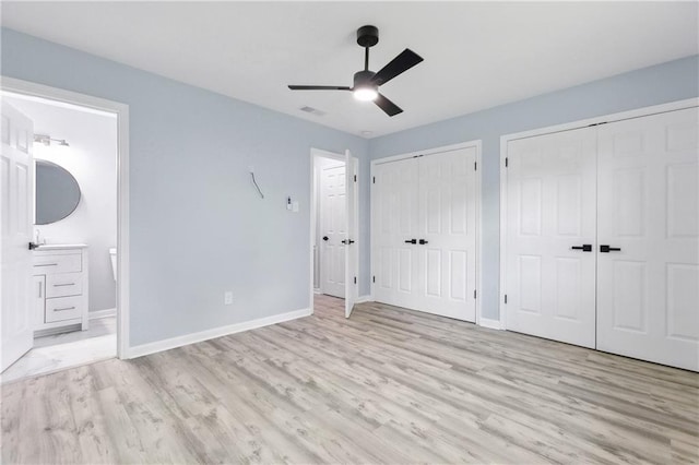 unfurnished bedroom with light hardwood / wood-style flooring, ensuite bath, multiple closets, and ceiling fan