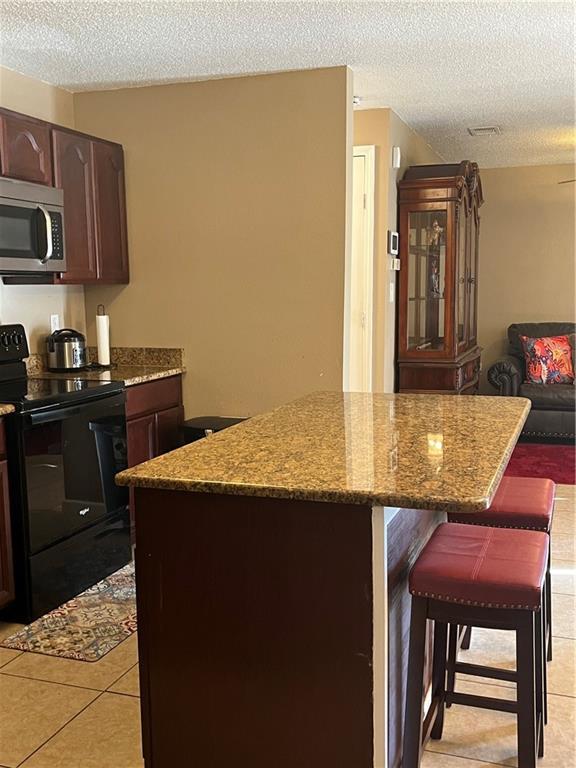 kitchen featuring black electric range oven, a textured ceiling, and a kitchen island