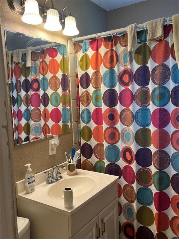 bathroom featuring vanity, curtained shower, and toilet