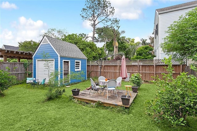 view of yard featuring a detached garage, a wooden deck, a storage shed, an outdoor structure, and a fenced backyard