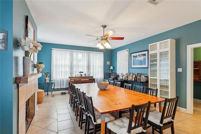 dining room with visible vents, baseboards, light tile patterned floors, a textured ceiling, and a ceiling fan