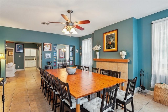 dining room with light tile patterned flooring, visible vents, a ceiling fan, and baseboards