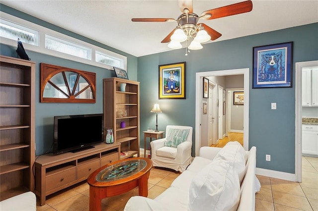 living room with ceiling fan, baseboards, and light tile patterned flooring