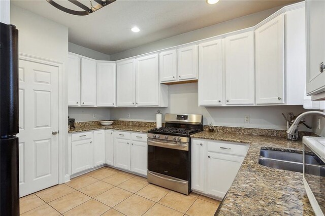 kitchen featuring black refrigerator, white cabinetry, sink, light tile patterned floors, and stainless steel range with gas stovetop