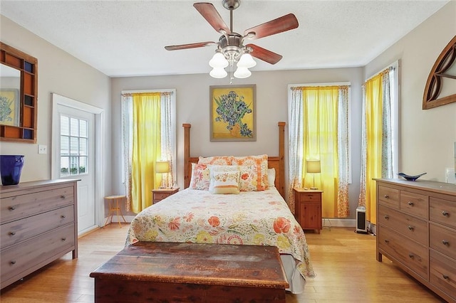 bedroom featuring a ceiling fan, light wood-type flooring, and a textured ceiling