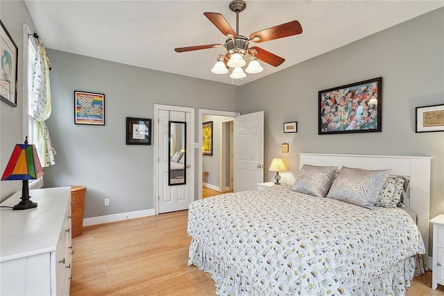 bedroom featuring ceiling fan, light wood-type flooring, and baseboards