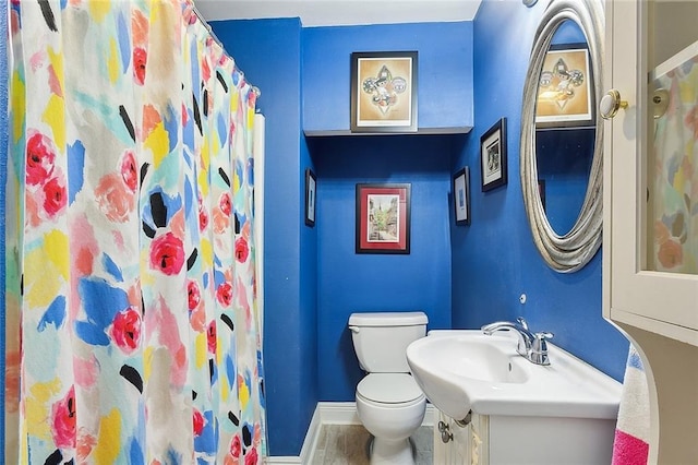 full bath featuring a shower with shower curtain, baseboards, toilet, and vanity