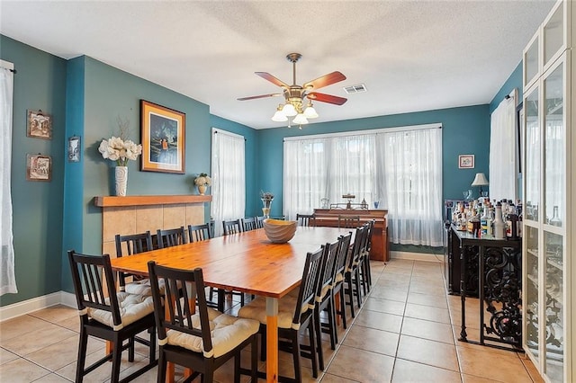 dining space with light tile patterned floors, baseboards, visible vents, and a textured ceiling