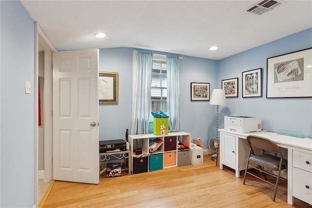 home office with visible vents, baseboards, vaulted ceiling, and light wood finished floors