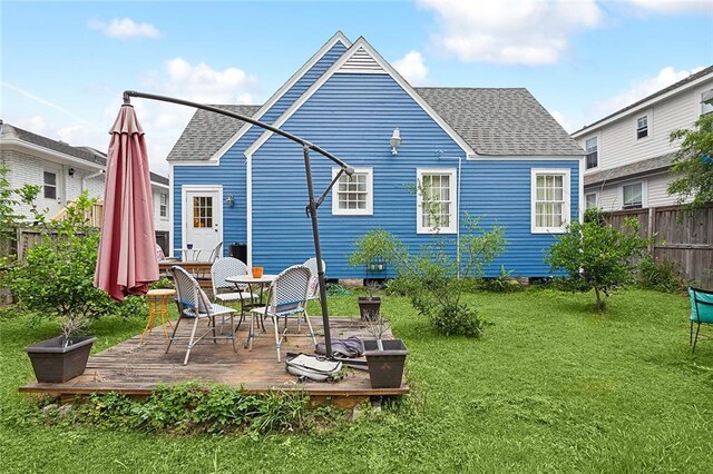 rear view of property featuring a wooden deck and a lawn