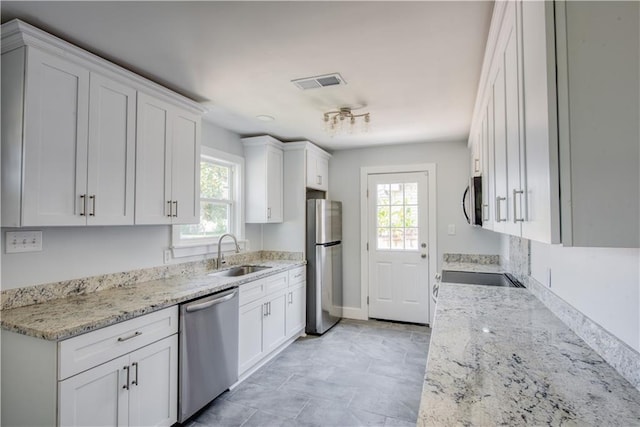 kitchen featuring light stone counters, appliances with stainless steel finishes, sink, and white cabinetry