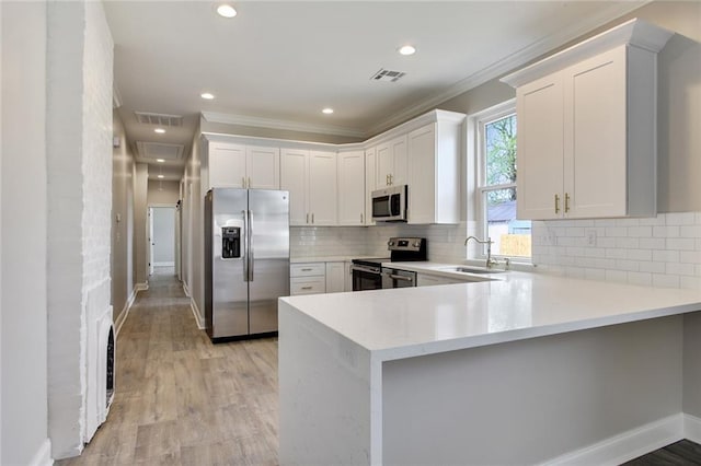 kitchen featuring white cabinetry, light wood-type flooring, kitchen peninsula, and appliances with stainless steel finishes