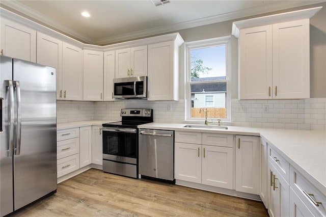 kitchen featuring sink, light hardwood / wood-style flooring, appliances with stainless steel finishes, white cabinets, and ornamental molding