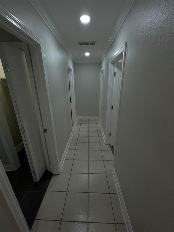 hall with ornamental molding and light tile patterned flooring