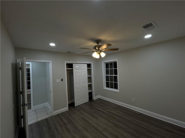 unfurnished bedroom with dark wood-type flooring, a closet, and ceiling fan