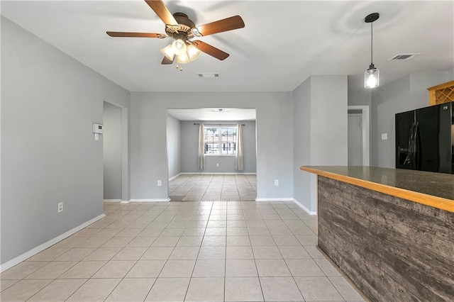 interior space featuring baseboards, visible vents, a ceiling fan, and light tile patterned flooring