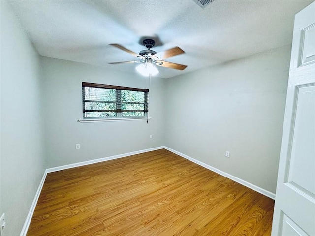 empty room with ceiling fan, wood-type flooring, and a textured ceiling