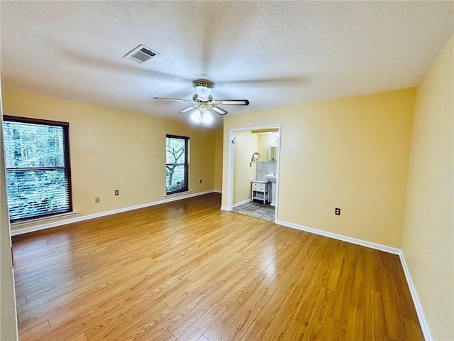 spare room featuring ceiling fan, light wood-type flooring, and a textured ceiling