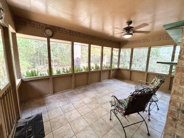 unfurnished sunroom featuring ceiling fan and a wealth of natural light