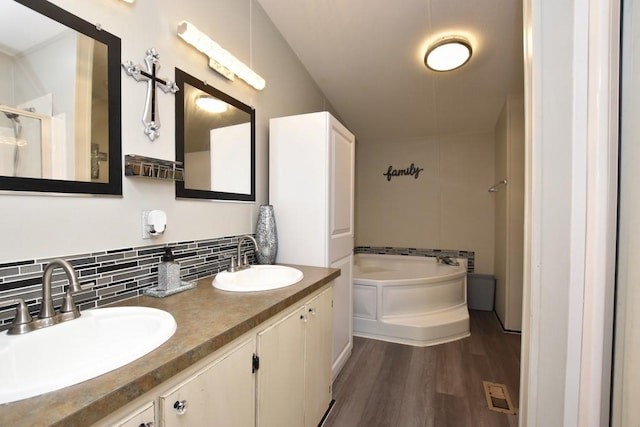 bathroom featuring backsplash, a tub to relax in, vanity, and wood-type flooring