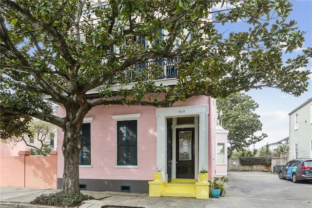 view of front of house featuring a balcony, crawl space, and fence