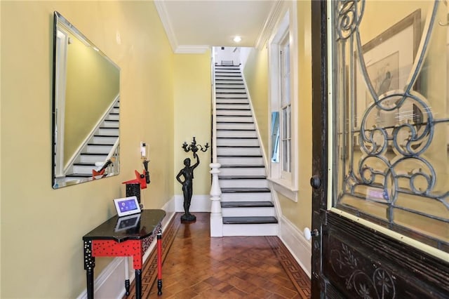 foyer entrance with baseboards, crown molding, and stairs