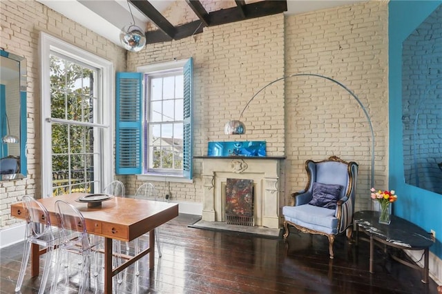 living area with vaulted ceiling with beams, dark wood-type flooring, and brick wall