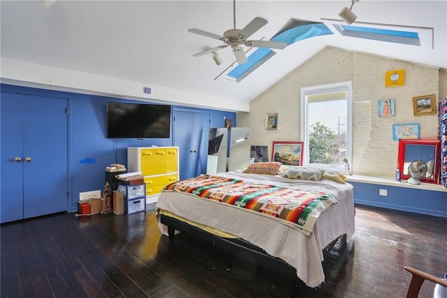 bedroom with ceiling fan, dark hardwood / wood-style flooring, and lofted ceiling with skylight