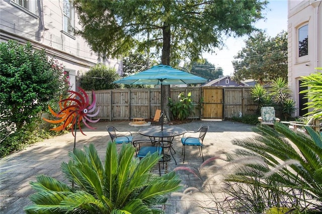 view of patio with a gate, outdoor dining area, and fence