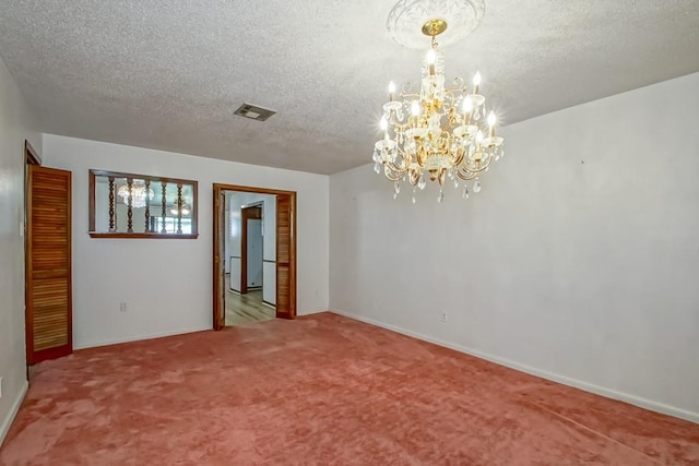 empty room featuring carpet flooring, an inviting chandelier, and a textured ceiling