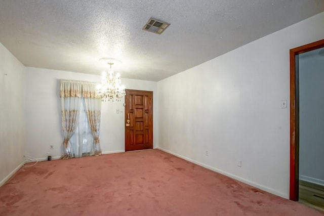 carpeted empty room with an inviting chandelier and a textured ceiling