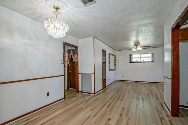 unfurnished room featuring ceiling fan with notable chandelier, a textured ceiling, and light hardwood / wood-style flooring