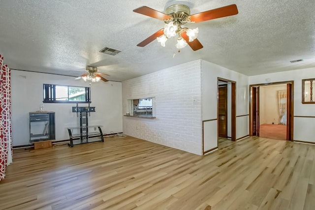 interior space featuring ceiling fan, light hardwood / wood-style floors, brick wall, and a textured ceiling