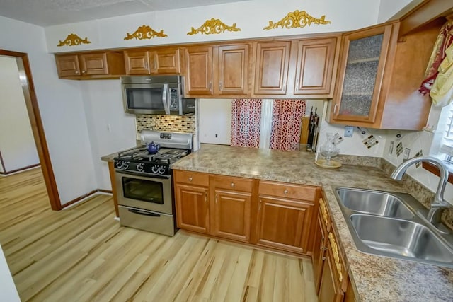 kitchen with stainless steel appliances, light hardwood / wood-style floors, decorative backsplash, and sink