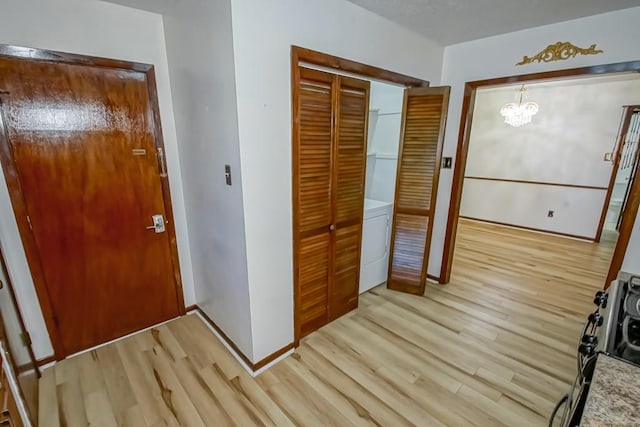 entryway with a chandelier, light hardwood / wood-style flooring, and washer / dryer