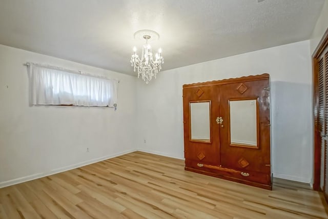 spare room with light hardwood / wood-style floors and a notable chandelier