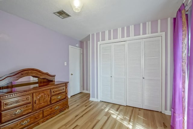 bedroom featuring a closet, light hardwood / wood-style floors, and a textured ceiling