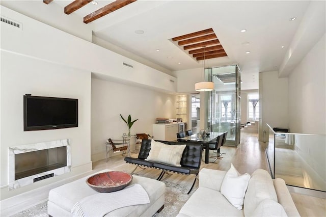 living room featuring a fireplace, light hardwood / wood-style flooring, and beam ceiling