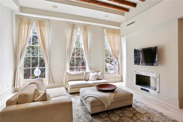 living area featuring hardwood / wood-style flooring, a premium fireplace, and beam ceiling