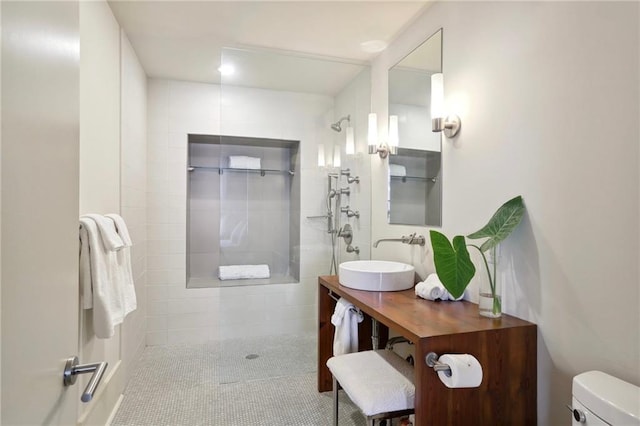 bathroom with toilet, a tile shower, tile patterned flooring, and vanity