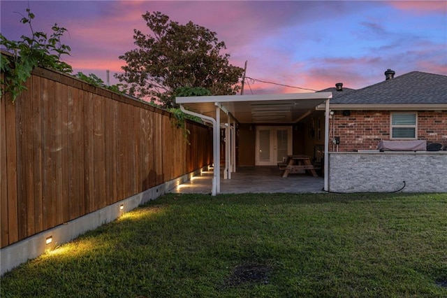 back house at dusk with a lawn and a patio area