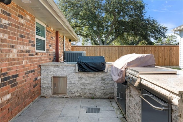 view of patio / terrace with an outdoor kitchen, cooling unit, and a grill