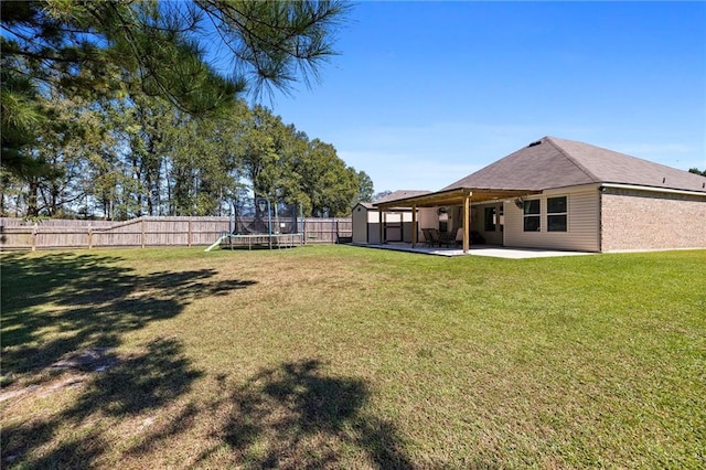 view of yard with a trampoline and a patio