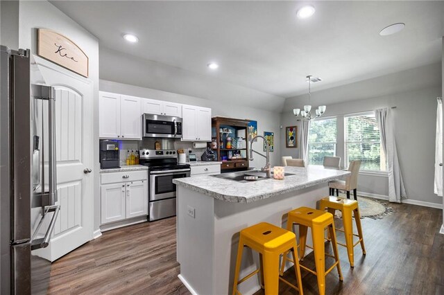 kitchen with stainless steel appliances, sink, pendant lighting, a center island with sink, and a kitchen breakfast bar