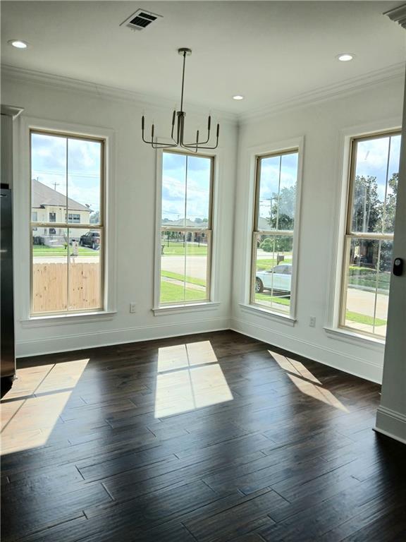 unfurnished dining area with dark wood-type flooring, plenty of natural light, and ornamental molding