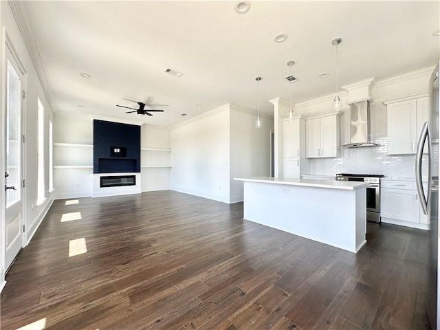 kitchen featuring decorative light fixtures, appliances with stainless steel finishes, wall chimney exhaust hood, and white cabinetry