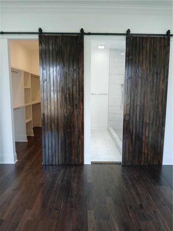 unfurnished room with ornamental molding, a barn door, and dark hardwood / wood-style flooring